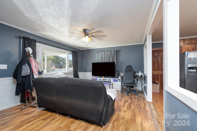 living room with ceiling fan, a textured ceiling, wood-type flooring, and ornamental molding