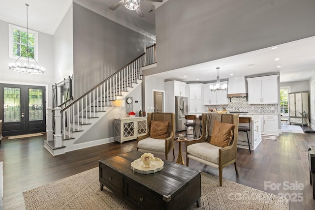 living room with french doors, dark hardwood / wood-style flooring, crown molding, and a towering ceiling