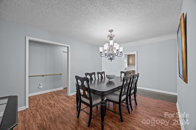 dining space featuring an inviting chandelier, a textured ceiling, and dark wood-type flooring