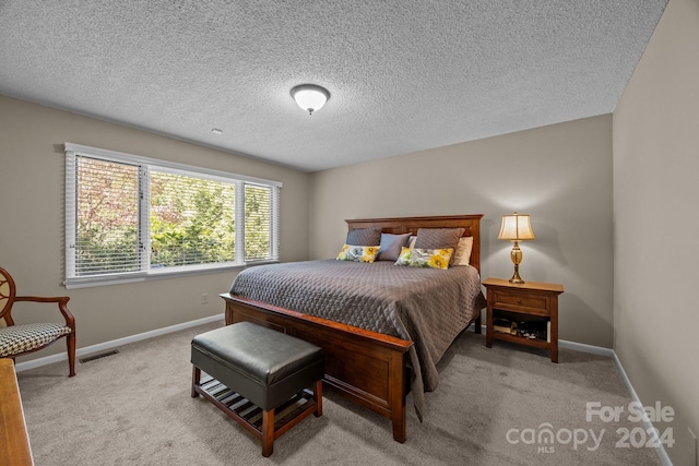 bedroom with light carpet and a textured ceiling