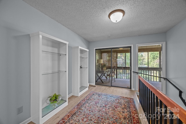 hall with light hardwood / wood-style floors and a textured ceiling