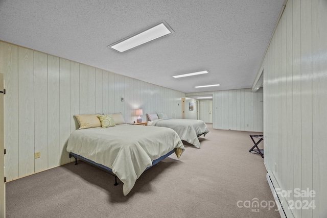 carpeted bedroom with wood walls, baseboard heating, and a textured ceiling