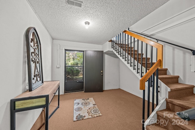 entrance foyer with light carpet and a textured ceiling