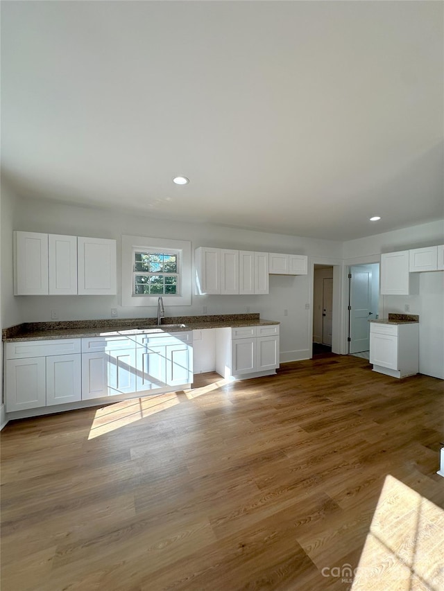 kitchen featuring white cabinetry, white fridge, sink, and light wood-type flooring