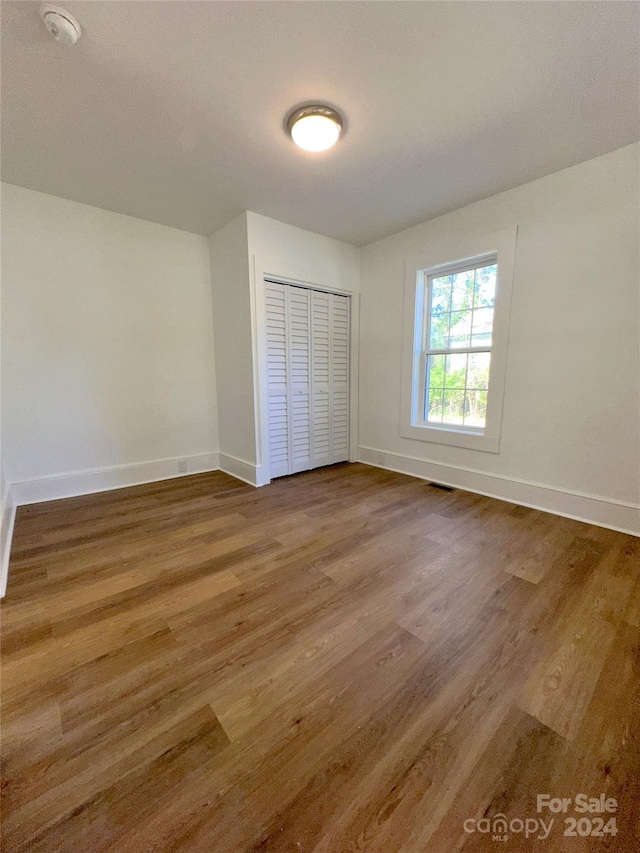 unfurnished bedroom featuring wood-type flooring and a closet