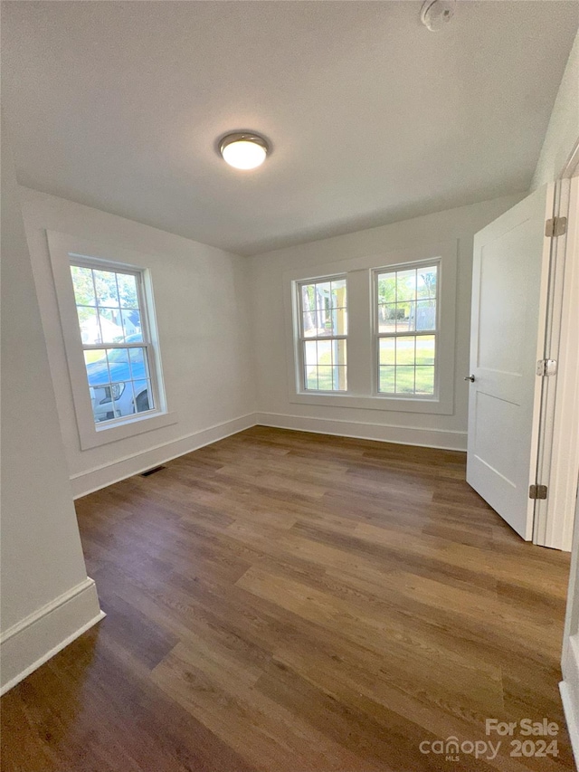 spare room with a wealth of natural light and dark hardwood / wood-style flooring