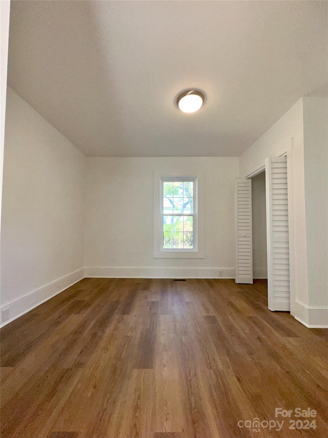 unfurnished bedroom with a closet and dark hardwood / wood-style floors