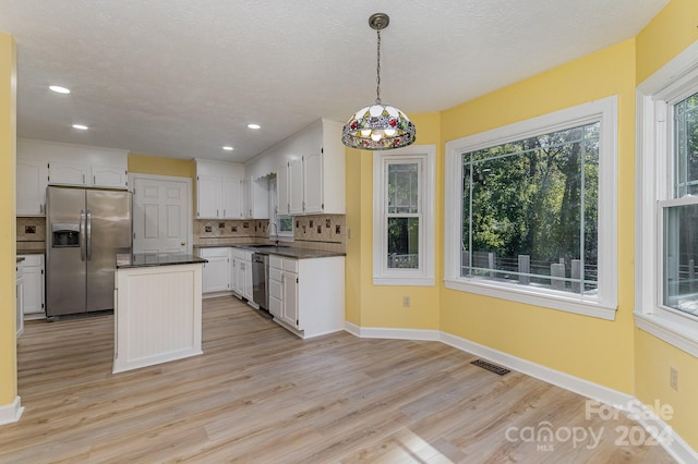 kitchen featuring appliances with stainless steel finishes, sink, light wood-type flooring, hanging light fixtures, and white cabinetry