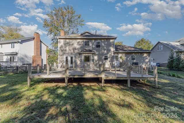 back of property featuring a deck and a lawn