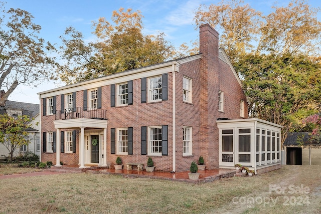 view of front of home featuring a sunroom, a front lawn, and a balcony