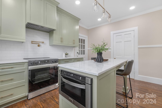 kitchen with appliances with stainless steel finishes, a kitchen breakfast bar, green cabinetry, a center island, and dark wood-type flooring