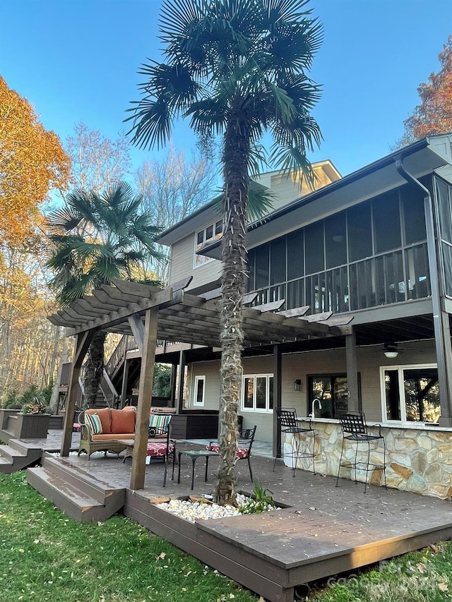 back of house with outdoor lounge area, a sunroom, a pergola, an outdoor bar, and a wooden deck