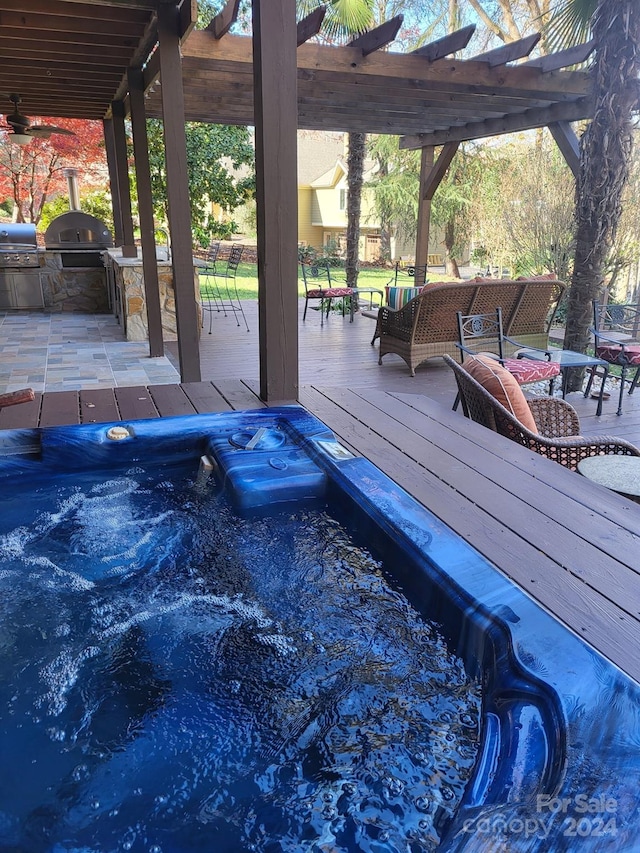 view of pool with a pergola, a wooden deck, a grill, and an outdoor kitchen