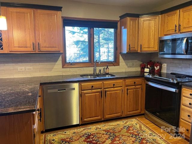 kitchen with decorative backsplash, sink, light wood-type flooring, and stainless steel appliances