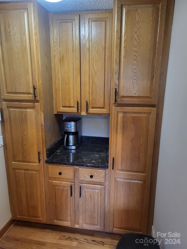 kitchen with dark stone countertops and light hardwood / wood-style floors