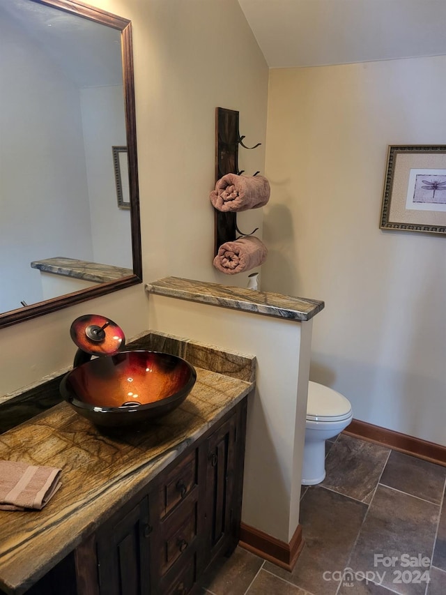 bathroom with tile patterned floors, vanity, lofted ceiling, and toilet