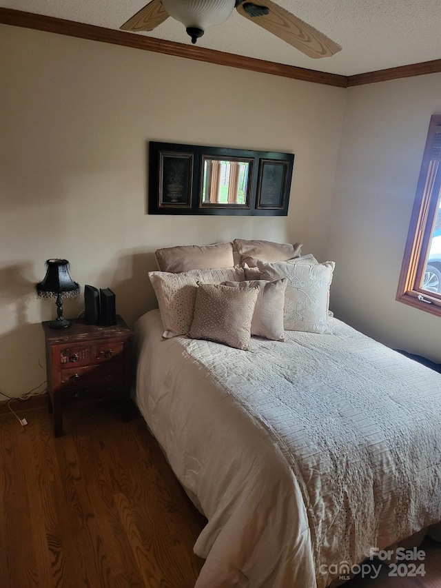 bedroom featuring a textured ceiling, crown molding, ceiling fan, and dark wood-type flooring