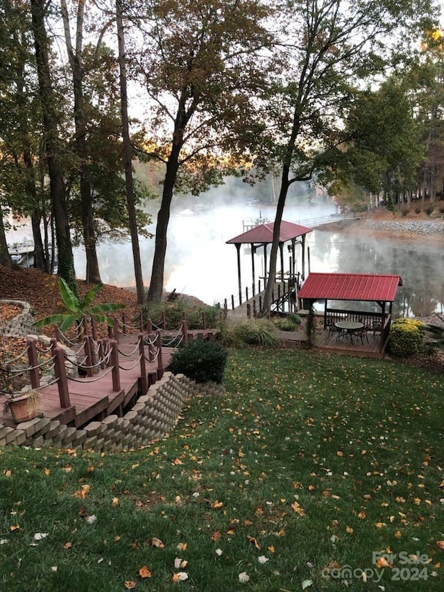 view of dock featuring a water view and a yard