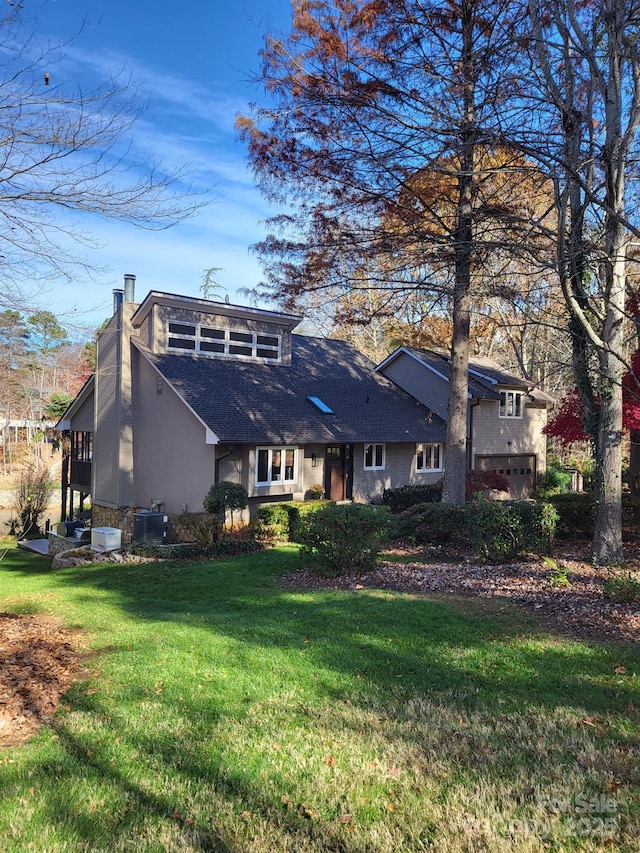 view of front of house featuring a shingled roof, a chimney, a front lawn, and stucco siding