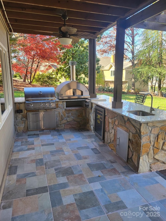 view of patio with an outdoor kitchen, a grill, ceiling fan, and a sink