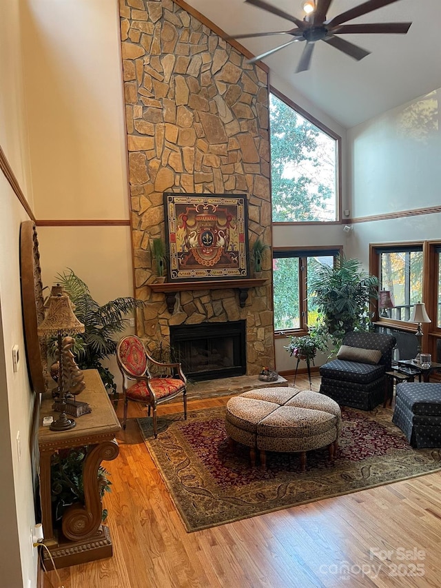 living area featuring ceiling fan, high vaulted ceiling, a fireplace, and wood finished floors