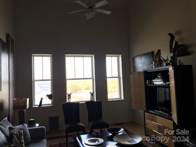 living room with ceiling fan, plenty of natural light, hardwood / wood-style floors, and a high ceiling