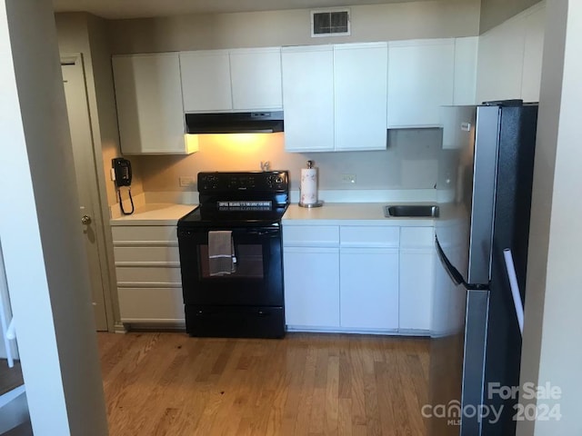 kitchen with refrigerator, white cabinetry, black electric range oven, and light hardwood / wood-style floors