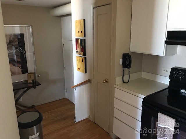 kitchen featuring white cabinetry, black electric range oven, light wood-type flooring, and ventilation hood