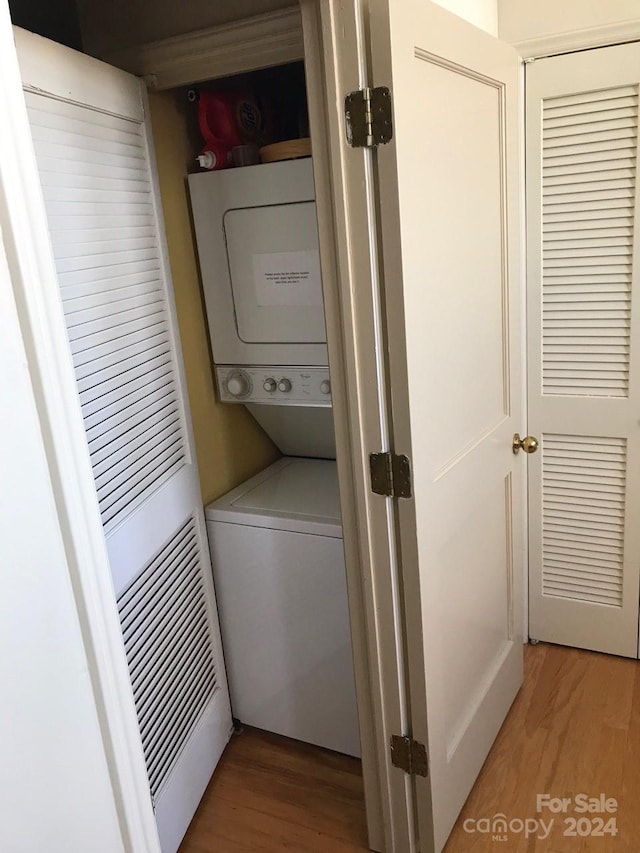 clothes washing area with wood-type flooring and stacked washer and clothes dryer