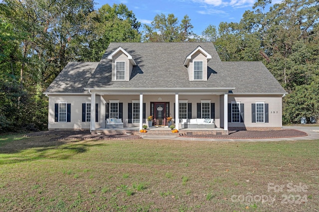 cape cod-style house featuring covered porch and a front yard