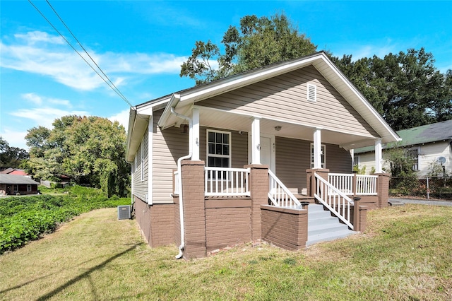 bungalow with a porch, a front yard, and central air condition unit