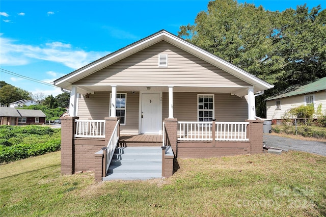 bungalow-style house featuring covered porch and a front yard