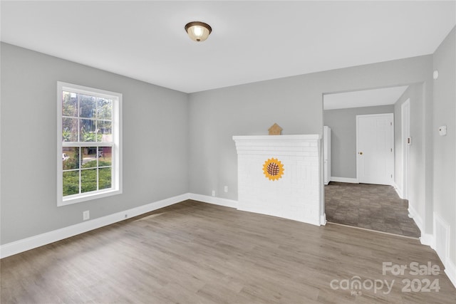 empty room with hardwood / wood-style flooring and a brick fireplace