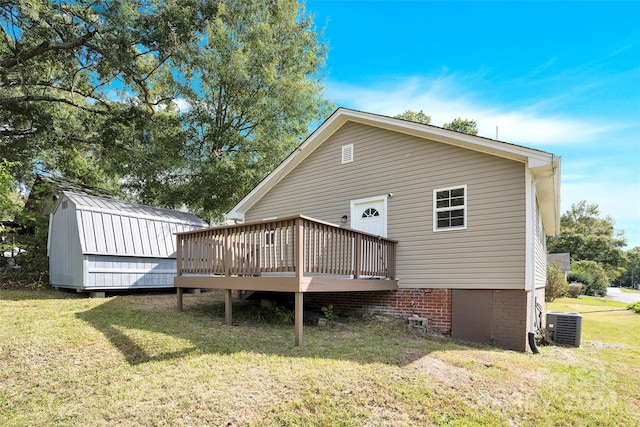 back of property featuring cooling unit, a storage unit, a yard, and a deck