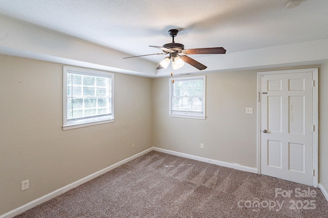 empty room with carpet floors, a textured ceiling, baseboards, and a ceiling fan