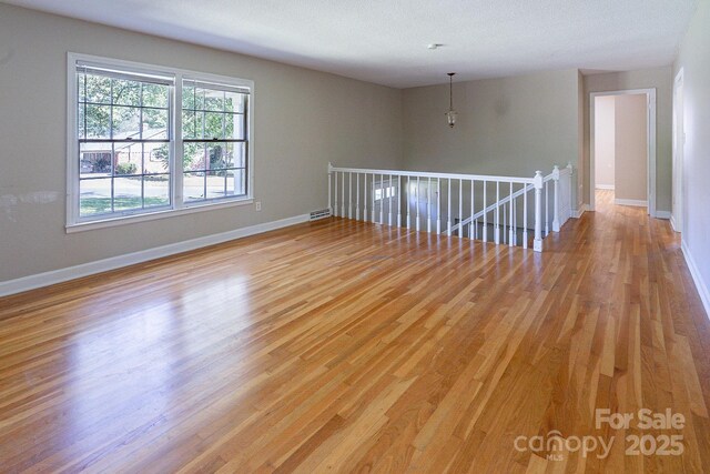 empty room featuring light wood-style floors, visible vents, and baseboards