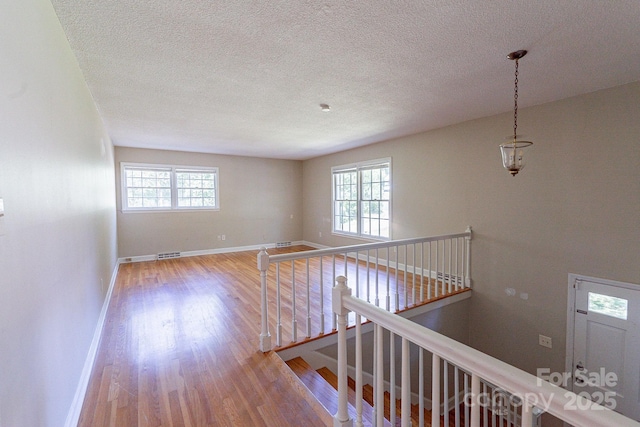 corridor featuring a wealth of natural light, baseboards, and wood finished floors