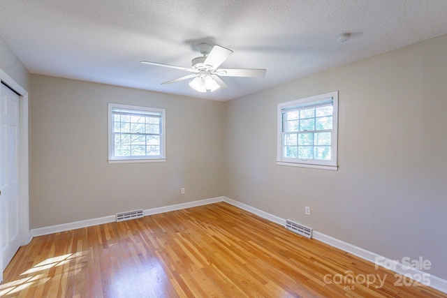 unfurnished bedroom with multiple windows, light wood-type flooring, and visible vents