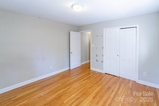 unfurnished bedroom featuring light wood-style floors, a closet, and baseboards