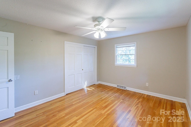 unfurnished bedroom with light wood-style flooring, visible vents, baseboards, and a closet