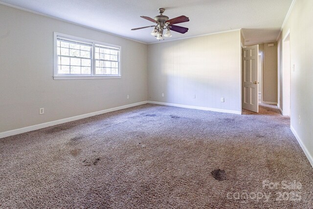 empty room featuring carpet flooring, crown molding, baseboards, and ceiling fan