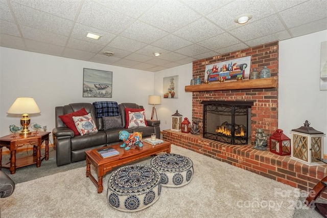 living room featuring carpet flooring, a drop ceiling, and a brick fireplace