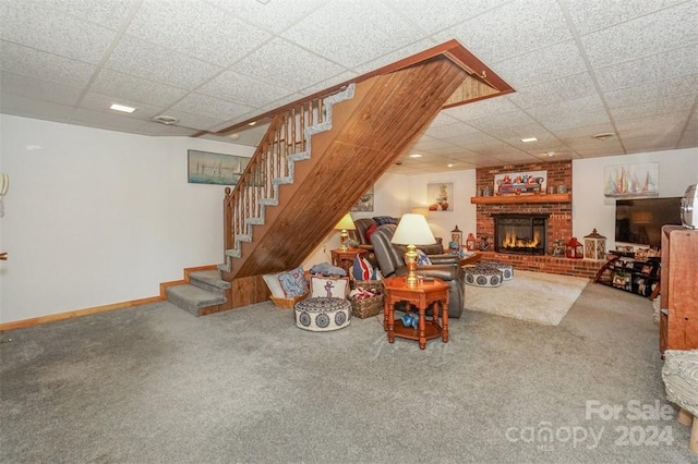 carpeted living room with a drop ceiling and a fireplace