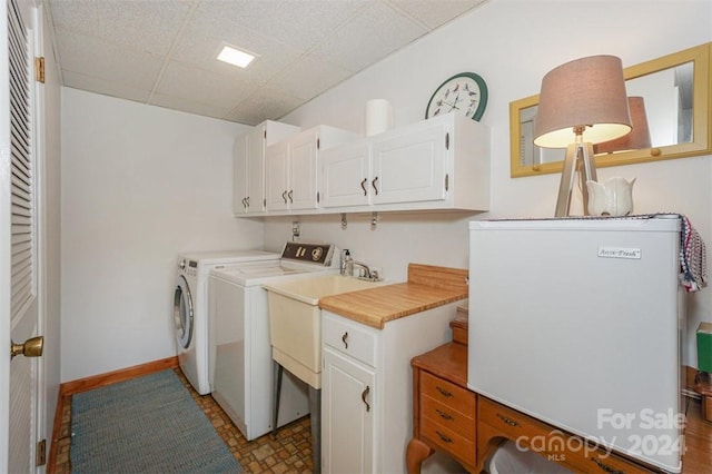 clothes washing area with washer and clothes dryer and cabinets