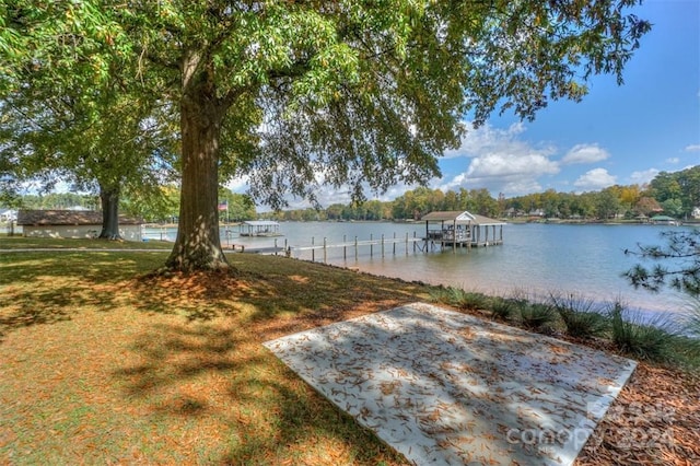 view of dock with a lawn and a water view