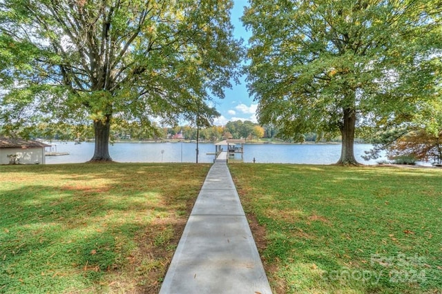 view of dock with a water view and a lawn