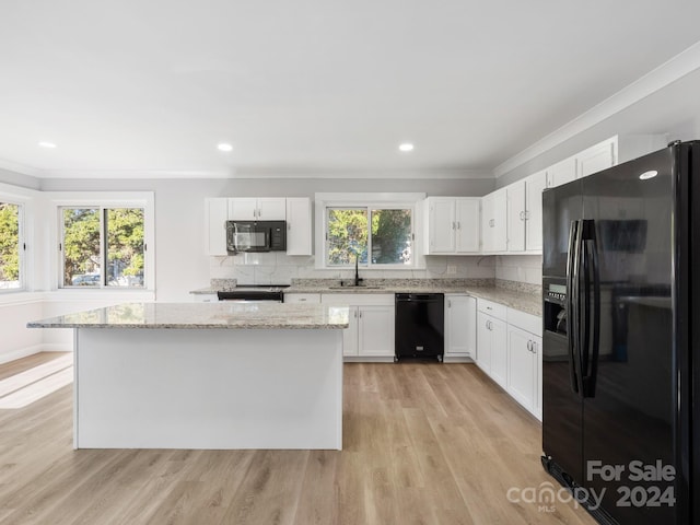 kitchen featuring a wealth of natural light, sink, black appliances, and white cabinets