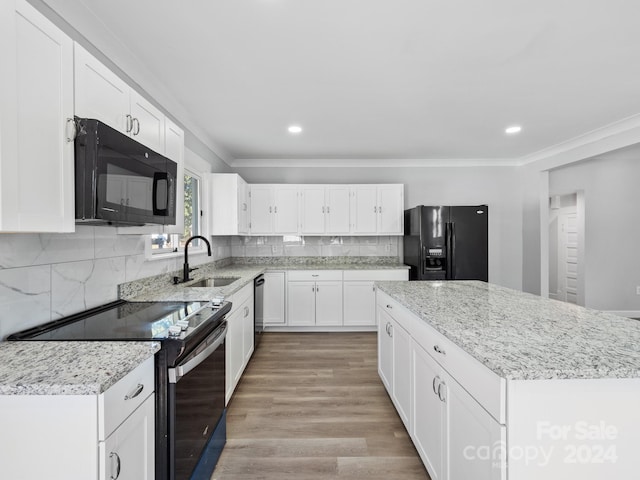 kitchen with sink, black appliances, crown molding, white cabinets, and light hardwood / wood-style floors