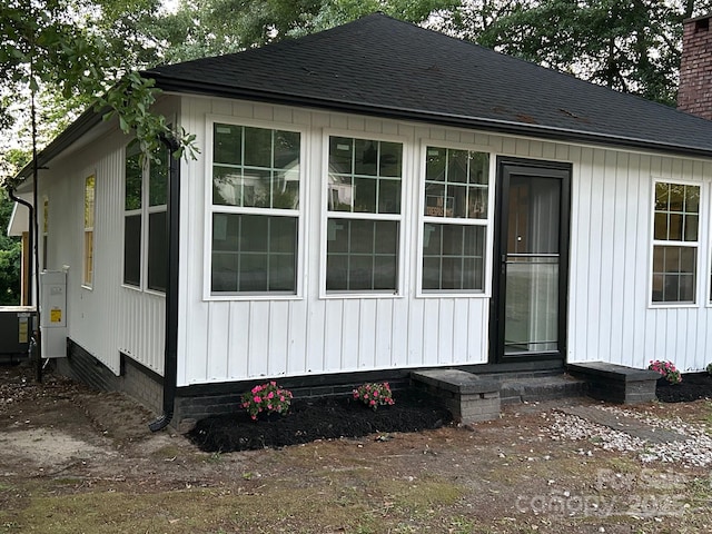 view of home's exterior with entry steps, roof with shingles, and a chimney