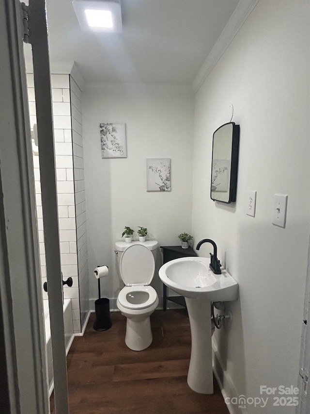 full bath featuring wood finished floors, toilet, a bathtub, and ornamental molding